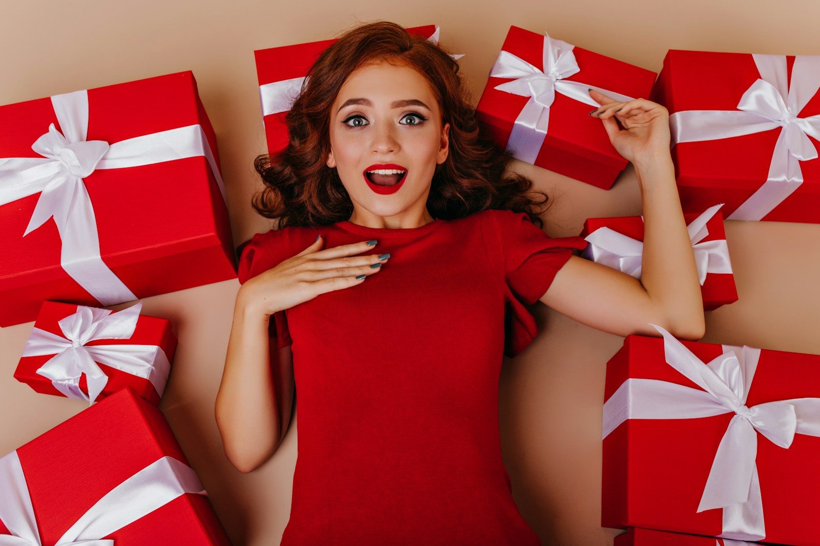 a woman in a red dress surrounded by red and white wrapped presents
